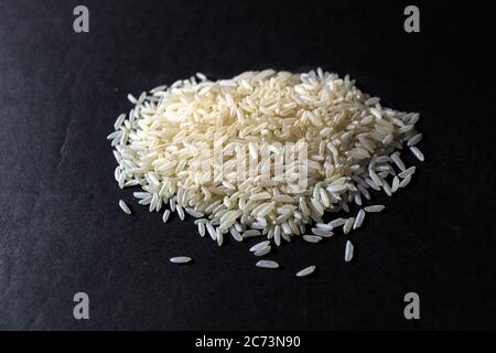 Riso bianco su sfondo nero. Primo piano grano di riso fresco grezzo isolato su sfondo nero. Foto Stock