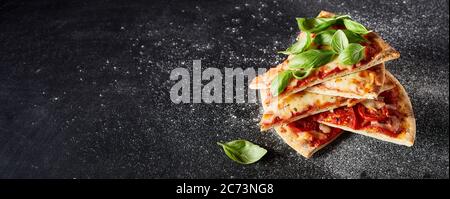 Banner panoramico con fette di pizza croccante appena cotta al forno su una base sottile e ricoperta da foglie di basilico fresco su ardesia infarinata con copyspace Foto Stock