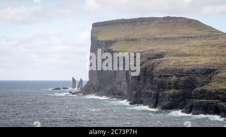 Risin e Kellingin rocce come visto dalla baia di Tjornuvik con le onde che colpiscono la riva di Streymoy sulle Isole Faroe, Danimarca, Europa Foto Stock