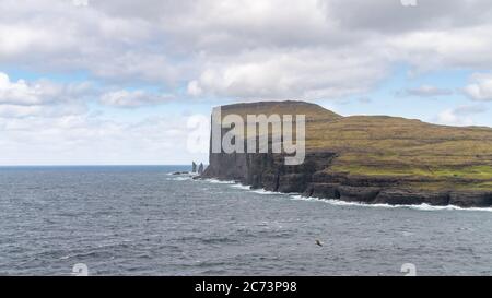 Risin e Kellingin rocce come visto dalla baia di Tjornuvik con le onde che colpiscono la riva di Streymoy sulle Isole Faroe, Danimarca, Europa Foto Stock