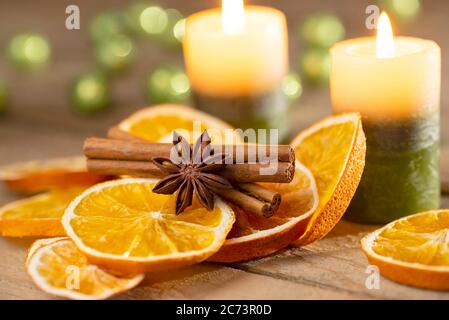 Decorazione di Natale o dell'avvento - candele con fette d'arancia e spezie su legno vecchio Foto Stock