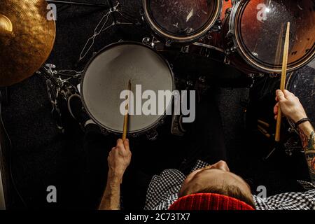 vista dall'alto sull'energico batterista caucasico suona professionalmente alla batteria, si diverte a suonare in studio, preparandosi per un concerto. rock and roll, m Foto Stock