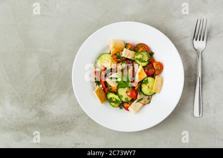 Su sfondo grigio in un piatto bianco insalata libanese Fattush. Verdure. Vegetarianismo. Disposizione piatta Foto Stock