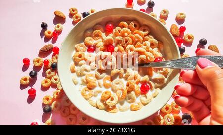 Ciotola di anelli per la colazione con latte e bacche isolati su sfondo bianco, top view.Delicious anelli di mais con bacche su table.Healthy colazione Foto Stock