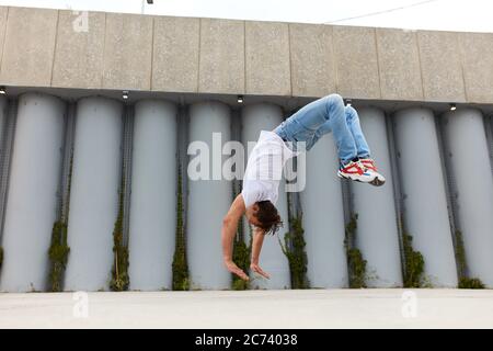 giovane uomo flessibile che fa il flip. sport estremo, parkour e concetto di persone. foto a vista laterale a tutta lunghezza. stile di vita, tempo libero, tempo libero, buiding bianco Foto Stock