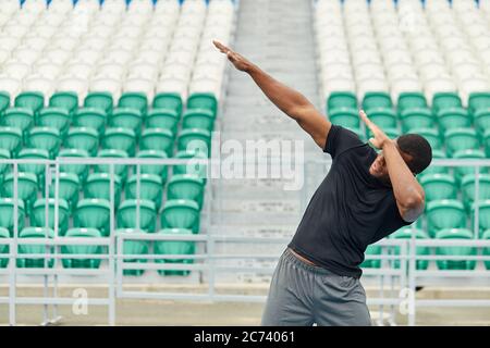 Allegro divertente giovane afroamericano che fa gesto dab, tirando le mani a destra inclinando, ballando, divertendosi all'aperto, primo piano foto. Entertainmnet, Foto Stock