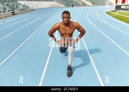 Bel forte sportivo che fa affondo, vestito di abbigliamento sportivo, all'aperto, foto a tutta lunghezza. Hobby, interesse Foto Stock