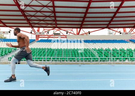 veloce e motivata, sprint di atleta sulla pista da corsa, foto a vista laterale a tutta lunghezza. spazio di copia. concetto di azione Foto Stock