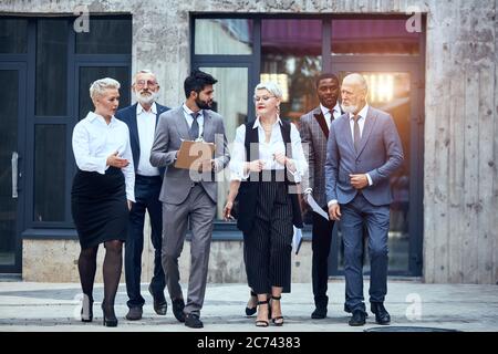 Gruppo di uomini d'affari vestiti in abiti eleganti da ufficio discutere progetto all'aperto Foto Stock