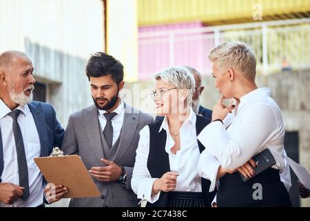 Quattro uomini d'affari caucasici ritratto tiro indossare diversi abiti da ufficio discutere progetto all'aperto Foto Stock