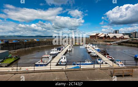 Newhaven Habour, all'estremità ovest del porto occidentale, Leith Docks Edimburgo, Scozia, con faro all'ingresso del porto e barche ormeggiate con bassa marea Foto Stock