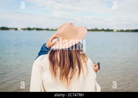 Donna turistica gode di vista lago paesaggio bere tè caldo coperto di coperta. Concetto di viaggio e turismo Foto Stock