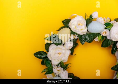 Una corona colorata di uova di Pasqua isolato su sfondo giallo. Concetto di vacanza di Pasqua con copyspace per il testo. Foto Stock