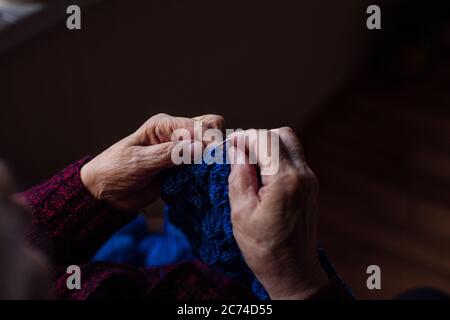 La vecchia donna si siede a casa e si unisce ai vestiti Foto Stock