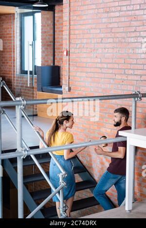 donna d'affari attraente che parla con l'uomo d'affari mentre si trova sulle scale Foto Stock