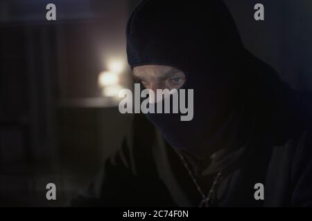 Hacker maschile nel cappuccio in una stanza buia utilizzando il programma di virus del computer per attacco informatico. Hacker e concetto di sicurezza informatica Foto Stock