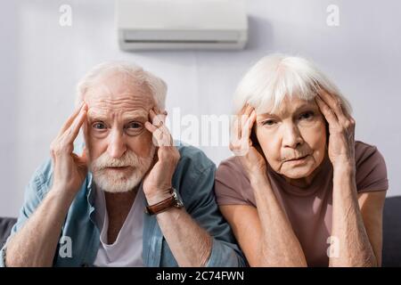 Coppia senior che guarda la fotocamera mentre soffre di calore a casa Foto Stock