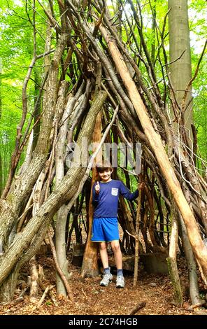 Faggio comune (Fagus sylvatica), ragazzino in una capanna fatta di tronchi e rami su un parco giochi forestale, Germania, Nord Reno-Westfalia Foto Stock