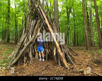 Faggio comune (Fagus sylvatica), ragazzino in una capanna fatta di tronchi e rami su un parco giochi forestale, Germania, Nord Reno-Westfalia Foto Stock