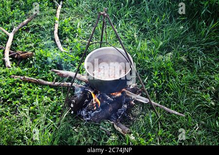 cottura al fuoco in una caldaia del campo, frittura di carne con carote Foto Stock