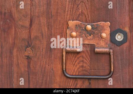 Maniglia in metallo forgiato con anello su una porta in legno. Foto Stock