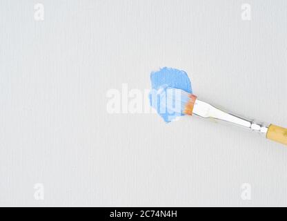 Pennello disegna vernice blu su tela, primo piano. Azione pittura arte. Artista ha cominciato a dipingere l'immagine, primi pennellate Foto Stock