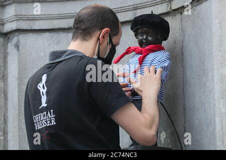 Bruxelles, Belgio. 14 luglio 2020. Un'addetta ufficiale vestisce il Manneken-Pis a Bruxelles, Belgio, 14 luglio 2020. Manneken-Pis, il simbolo del folklore di Bruxelles, si prende costumi in occasione di grandi eventi. Il martedì indossava un vestito con beretto e baguette per commemorare la giornata nazionale francese che cade il 14 luglio di ogni anno. Credit: Zheng Huansong/Xinhua/Alamy Live News Foto Stock