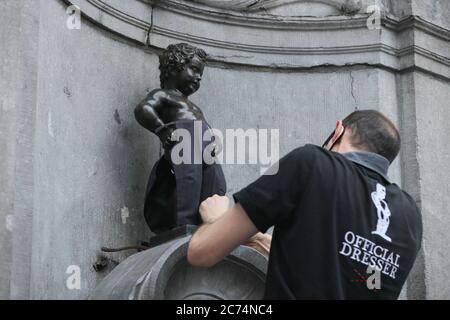 Bruxelles, Belgio. 14 luglio 2020. Un'addetta ufficiale vestisce il Manneken-Pis a Bruxelles, Belgio, 14 luglio 2020. Manneken-Pis, il simbolo del folklore di Bruxelles, si prende costumi in occasione di grandi eventi. Il martedì indossava un vestito con beretto e baguette per commemorare la giornata nazionale francese che cade il 14 luglio di ogni anno. Credit: Zheng Huansong/Xinhua/Alamy Live News Foto Stock