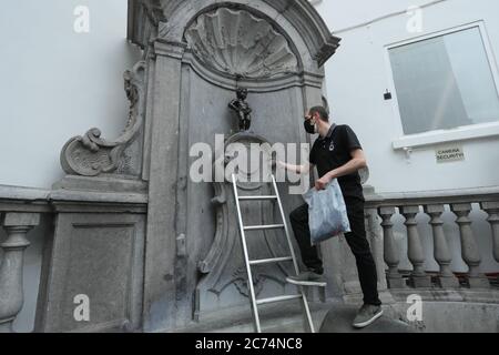 Bruxelles, Belgio. 14 luglio 2020. Un'addetta ufficiale si prepara a vestire il Manneken-Pis a Bruxelles, Belgio, 14 luglio 2020. Manneken-Pis, il simbolo del folklore di Bruxelles, si prende costumi in occasione di grandi eventi. Il martedì indossava un vestito con beretto e baguette per commemorare la giornata nazionale francese che cade il 14 luglio di ogni anno. Credit: Zheng Huansong/Xinhua/Alamy Live News Foto Stock