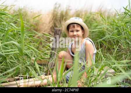 un ragazzino in cappello sta pescando nelle canne. Foto Stock