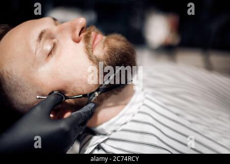 Barbiere radere un uomo nel barbiere, primo piano Foto Stock