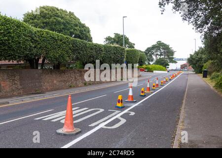 Sandbanks, Poole, Dorset UK. 14 luglio 2020. La collina serale di Sandbanks è un luogo popolare per le persone per fermarsi, ammirare e fotografare le viste spettacolari e i tramonti che si affacciano sul Poole Harbour. E' la strada principale da/per Sandbanks che si congestiona in tempi molto trafficati. 43 posti di parcheggio su strada sono stati rimossi e sostituiti con una pista ciclabile di prova con 240 metri di pilastri flessibili per incoraggiare le persone a pedalare a sostegno delle ambizioni climatiche ed ecologiche del Consiglio e nel quadro delle misure per il programma del Fondo di viaggio attivo di emergenza del Dipartimento dei trasporti. Credit: Carolyn Jenkins/Alamy Live News Foto Stock