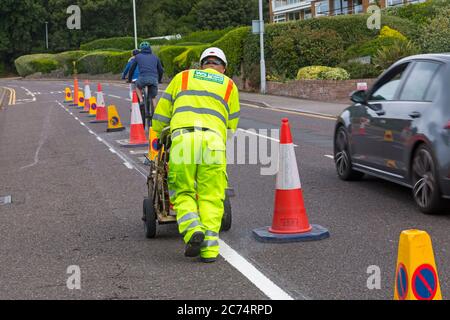 Sandbanks, Poole, Dorset UK. 14 luglio 2020. La collina serale di Sandbanks è un luogo popolare per le persone per fermarsi, ammirare e fotografare le viste spettacolari e i tramonti che si affacciano sul Poole Harbour. E' la strada principale da/per Sandbanks che si congestiona in tempi molto trafficati. 43 posti di parcheggio su strada sono stati rimossi e sostituiti con una pista ciclabile di prova con 240 metri di pilastri flessibili per incoraggiare le persone a pedalare a sostegno delle ambizioni climatiche ed ecologiche del Consiglio e nel quadro delle misure per il programma del Fondo di viaggio attivo di emergenza del Dipartimento dei trasporti. Credit: Carolyn Jenkins/Alamy Live News Foto Stock