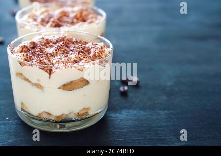 tiramisù in bicchieri decorati con polvere di cacao su sfondo scuro Foto Stock