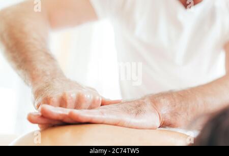 Mani dell'uomo del massaggiatore che fanno manipolazioni del massaggio sulla zona di Scapula durante il massaggio del corpo femminile. Foto Stock