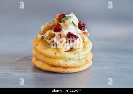 Formaggio fresco fatto in casa mirtillo spalmato con formaggio cremoso, cheddar bianco, mirtillo rosso, noci e erba cipollina su ardesia. Messa a fuoco selettiva con b Foto Stock