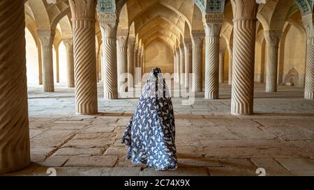 Shiraz, Iran - Maggio 2019: Donna non identificata che cammina nella sala di preghiera della Moschea di Vakil con colonne. Vakil significa reggente, titolo di Karim Khan, fondatore di Z Foto Stock