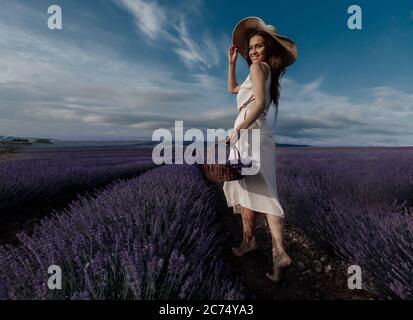 Giovane bella donna che cammina in campo lavanda vista posteriore grandangolare Foto Stock