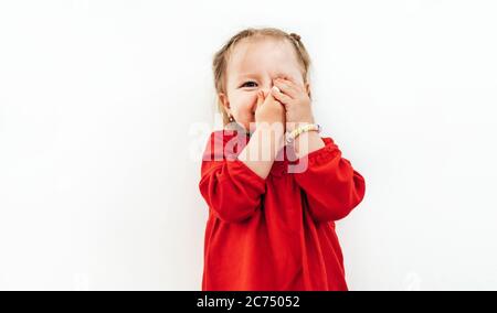 Emozioni confuse della bambina vestita blusa rossa sullo sfondo bianco. Foto Stock