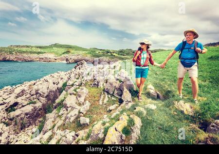 Un paio di viaggiatori zaino in spalla cammina sulla costa rocciosa dell'oceano. Asturie. Spagna Foto Stock