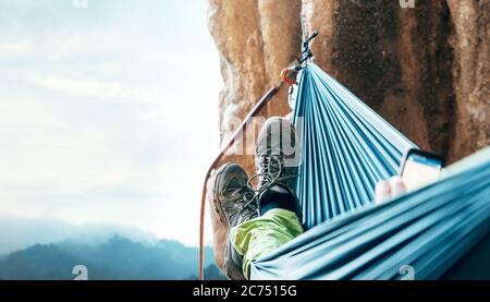 Scalatore riposante in amaca sulla parete verticale della scogliera Foto Stock