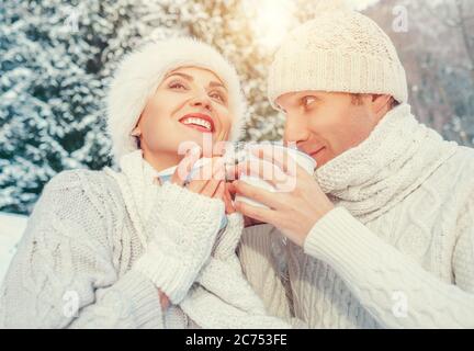 Accogliente coppia vestito in amore bevanda calda di tè nella foresta invernale Foto Stock