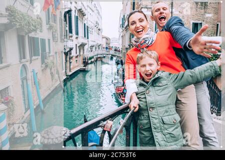 Felice famiglia scatta una foto selfie su quello del ponte di Venezia. Viaggia intorno al wolrd con l'immagine concettuale dei bambini Foto Stock