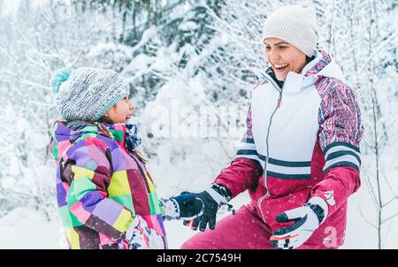 Felice ritratto di madre e figlia sorridenti nella foresta di neve. Felice genitori e figli relazione idea immagine Foto Stock