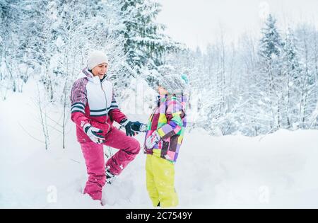 Felice ritratto di madre e figlia sorridenti nella foresta di neve. Felice genitori e figli relazione idea immagine Foto Stock