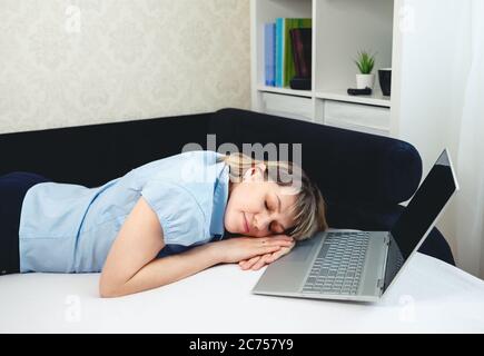 Donna stanca che dorme. Sonnolenta ragazza che lavora a distanza davanti al laptop Foto Stock