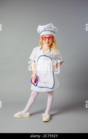 La bambina in un'uniforme medica si prepara a trattare le persone Foto Stock