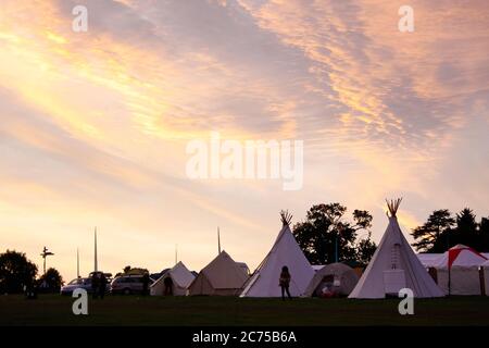 Tipis in campo glamping con ad un campeggio festival al tramonto, Norfolk Foto Stock