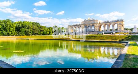 VIENNA, AUSTRIA - 23 LUGLIO 2019: La Gloriette nei giardini del Palazzo di Schonbrunn, Vienna, Austria. Vista frontale e riflesso dell'acqua. Foto Stock