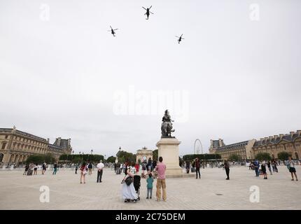 Parigi, Francia. 14 luglio 2020. La gente guarda lo spettacolo aereo al Museo del Louvre durante la celebrazione del giorno della Bastiglia presso Place de la Concorde a Parigi, Francia, 14 luglio 2020. Senza la tradizionale parata militare lungo il famoso viale degli Champs Elysees e la celebrazione pubblica, il presidente francese Emmanuel Macron martedì ha presieduto la cerimonia del giorno della Bastiglia offuscata dalla crisi del coronavirus. Credit: Xinhua/Alamy Live News Foto Stock